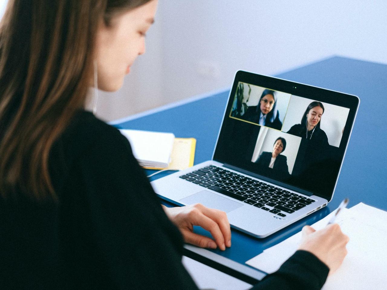 Een vrouw videobelt met drie personen op haar laptop